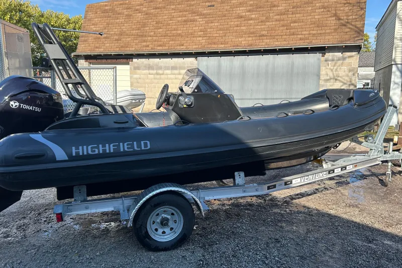The Image of 2025 Highfield Sport 520 boat on trailer, featuring Tohatsu engine, parked outdoors. - 4