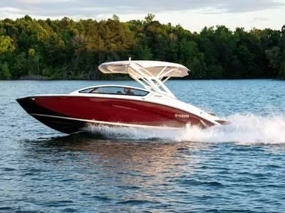 Slide: The Image of 2021 Yamaha Boats 275SE cruising on a lake with lush green forest backdrop. - 13