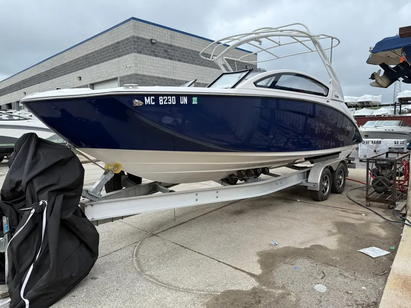 Slide: The Image of 2021 Yamaha Boats 275SE on trailer, blue hull, parked outdoors near industrial building. - 3