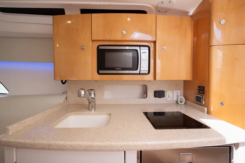 Slide: The Image of 2013 Intrepid 400 Cuddy kitchen with microwave, sink, and stovetop. - 26