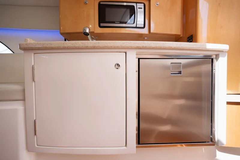 Slide: The Image of 2013 Intrepid 400 Cuddy kitchen with microwave, cabinets, and stainless steel fridge. - 30