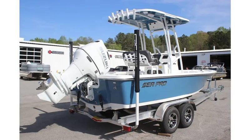 Slide: The Image of 2025 Sea Pro 210 boat on trailer with Suzuki outboard motor, parked outdoors. - 2
