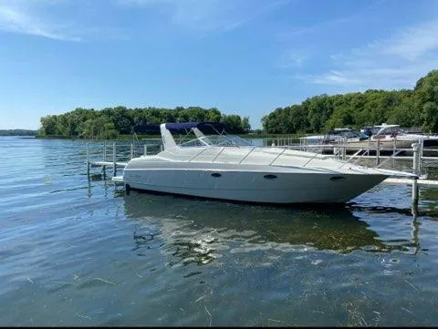 Slide: The Image of 1994 Chris-Craft 340 Crowne boat docked on a serene lake under a clear blue sky. - 12