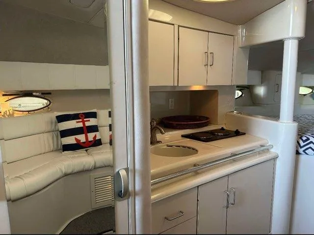 Slide: The Image of 1994 Chris-Craft 340 Crowne interior with kitchenette, seating, and nautical decor. - 6