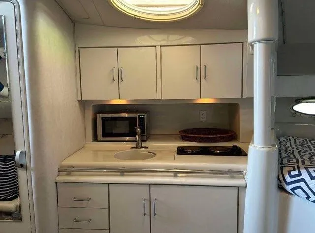 Slide: The Image of 1994 Chris-Craft 340 Crowne yacht interior kitchen with cabinets, sink, microwave, and stove. - 7