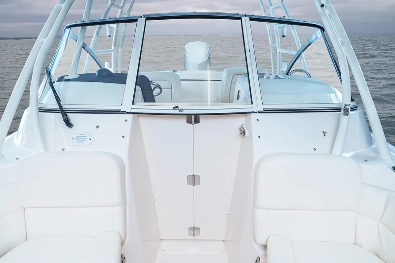 Slide: The Image of 2025 Grady-White Freedom 255 boat interior with white seating and windshield on calm water. - 10
