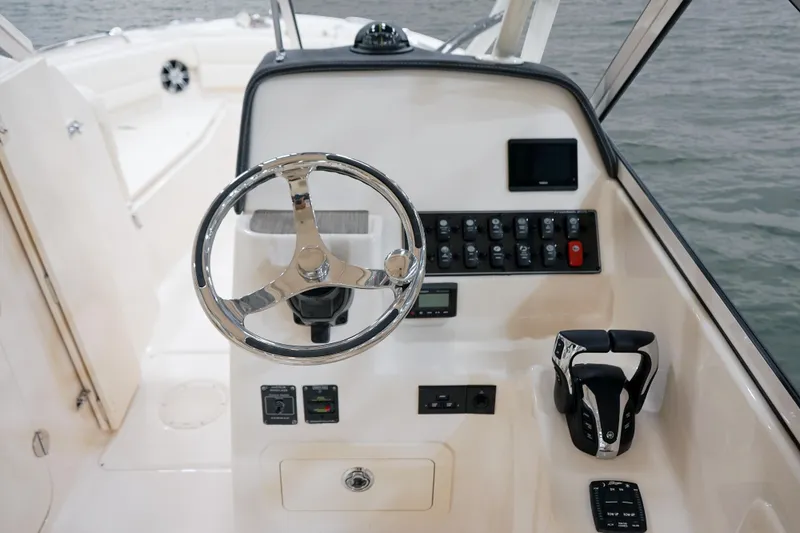 Slide: The Image of 2025 Grady-White Freedom 255 boat dashboard with steering wheel and control panel. - 11