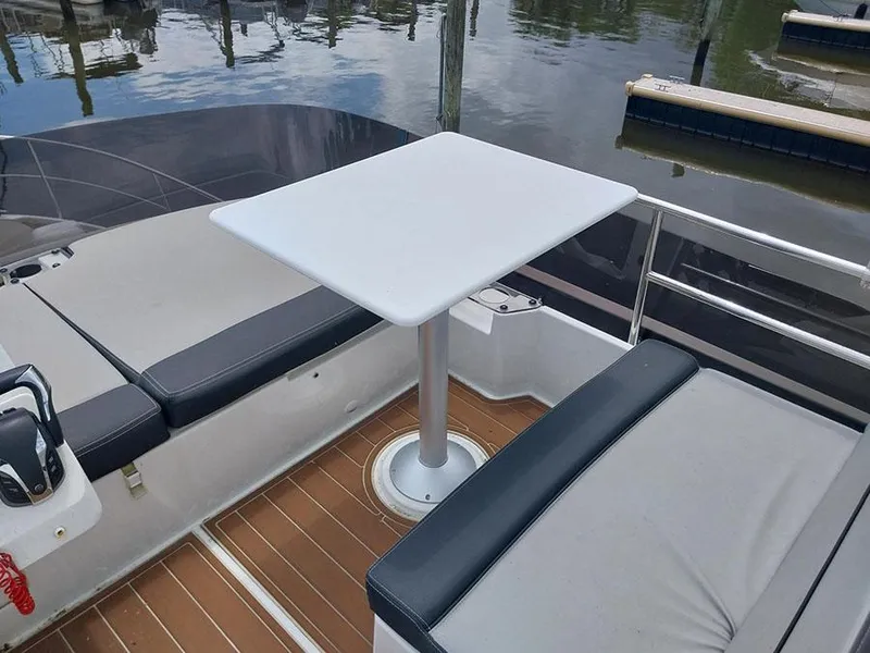 Slide: The Image of 2023 Jeanneau NC 1095 Fly boat deck with seating and table, docked by water. - 21