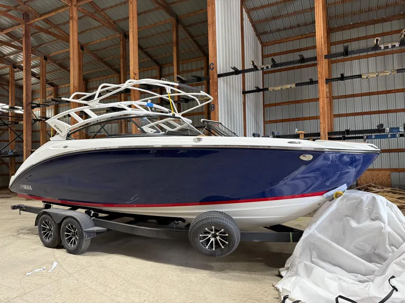 Slide: The Image of 2025 Yamaha Boats 252SD in storage, blue hull, on trailer, indoor facility. - 0