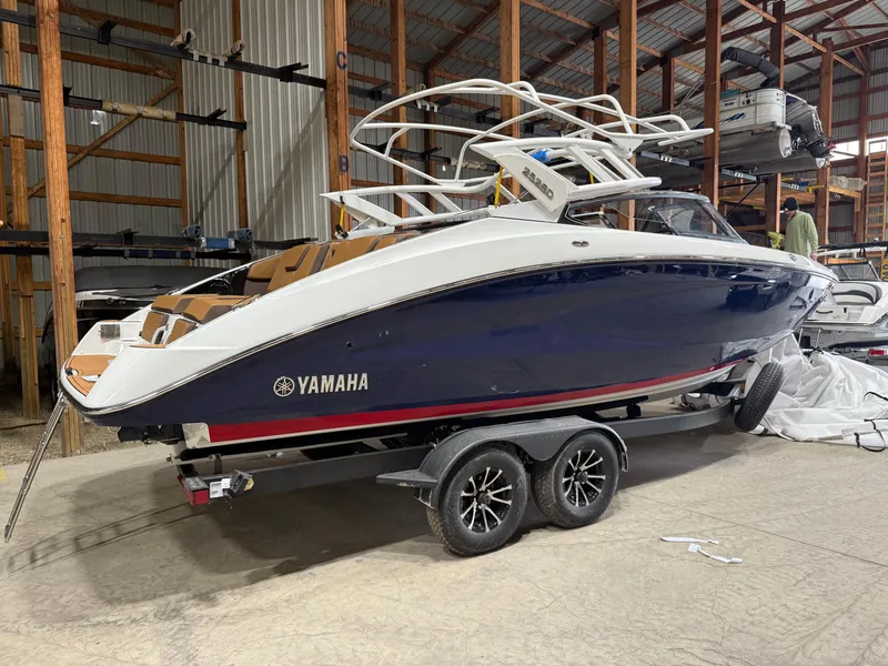 Slide: The Image of 2025 Yamaha Boats 252SD in storage, blue hull, on a trailer. - 2