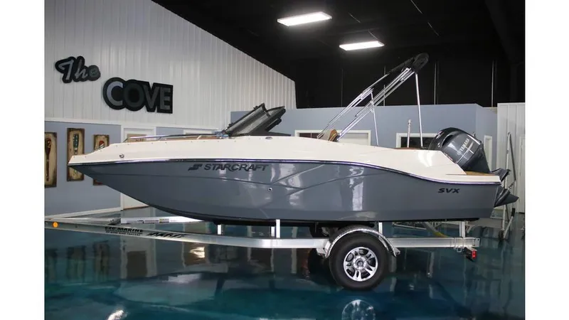 The Image of 2025 Starcraft SVX 190 OB DC boat on trailer in showroom. - 1