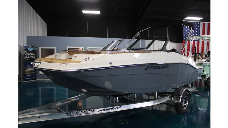 Slide: The Image of 2025 Starcraft SVX 190 OB DC boat on trailer in showroom with American flag. - 11