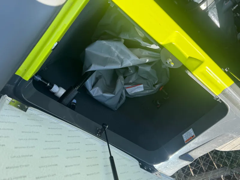 Slide: The Image of Storage compartment of a 2018 MasterCraft XT22 boat, featuring a gray interior and yellow trim. - 14