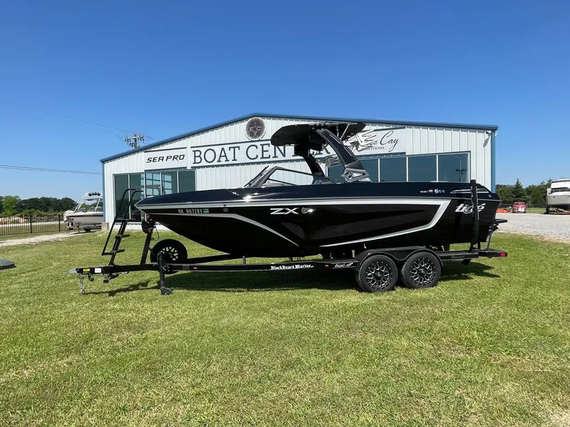 Slide: The Image of 2021 Tigé 23ZX boat on trailer at a boat center, parked on grass. - 1