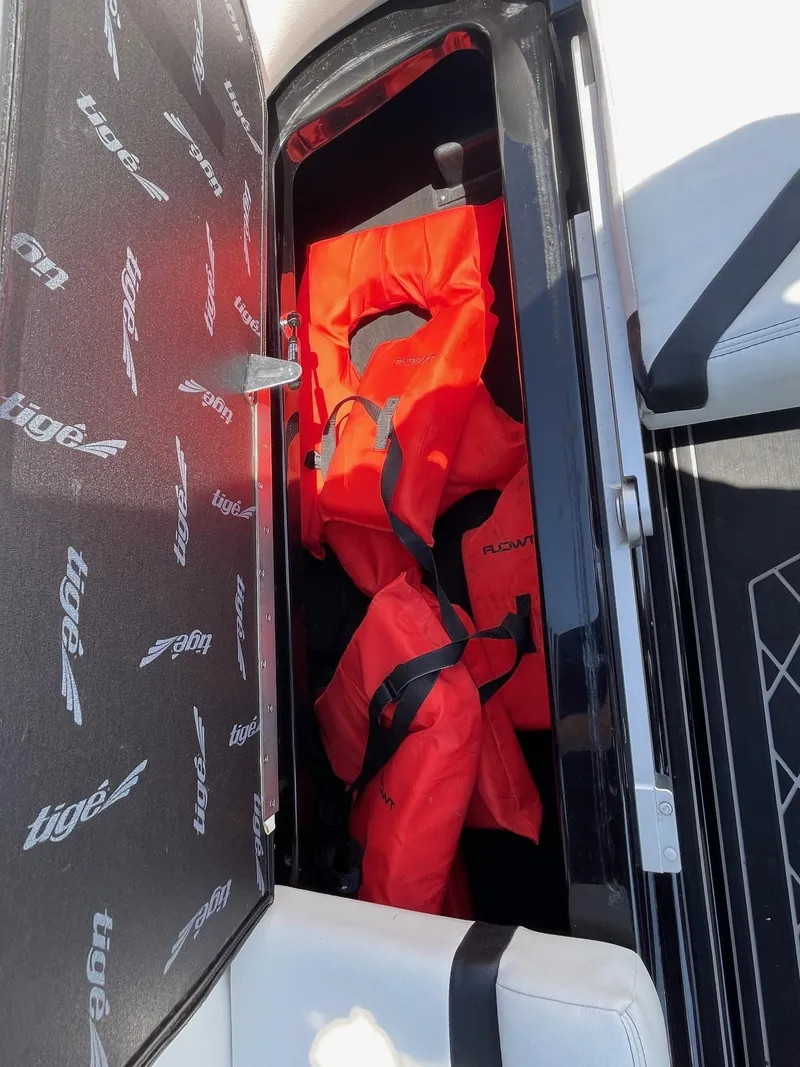 Slide: The Image of 2021 Tigé 23ZX boat storage compartment with orange life jackets. - 16