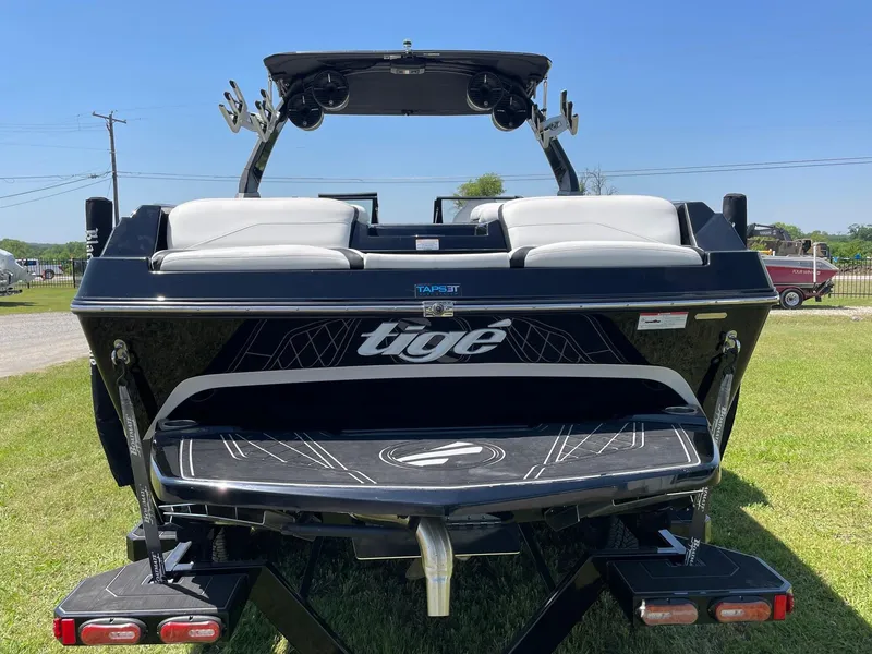 Slide: The Image of 2021 Tigé 23ZX boat rear view on grass, showcasing sleek design and seating. - 2