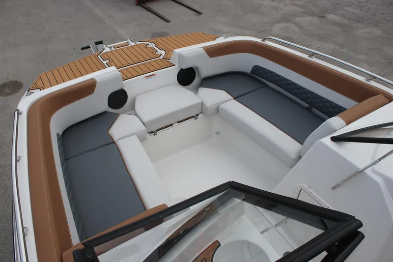 Slide: The Image of 2025 Starcraft SVX 210 OB DC boat interior with cushioned seating and teak accents. - 16