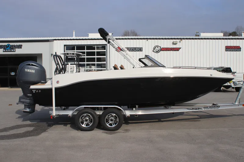 Slide: The Image of 2025 Starcraft SVX 210 OB DC boat on trailer, black and white design, parked outside dealership. - 7