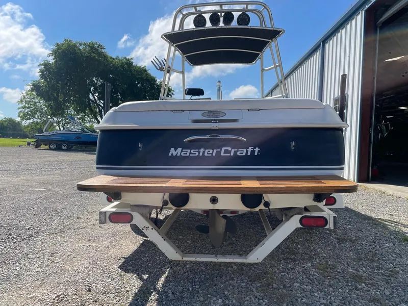 Slide: The Image of 1999 MasterCraft Prostar 205 boat, rear view, parked outdoors near a metal building. - 9