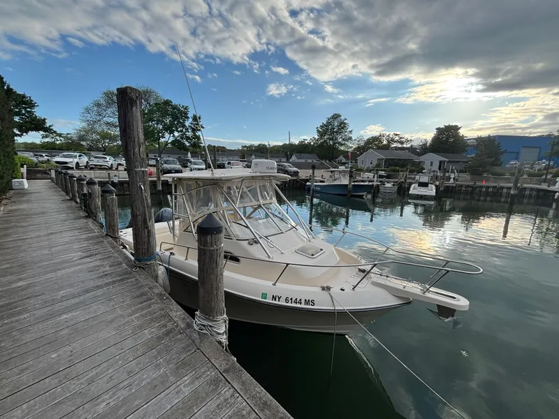 Slide: The Image of 2021 Grady-White Gulfstream 232 docked at a serene marina under a partly cloudy sky. - 16