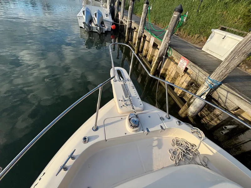 Slide: The Image of 2021 Grady-White Gulfstream 232 boat docked, showing bow and railing near wooden pier. - 21