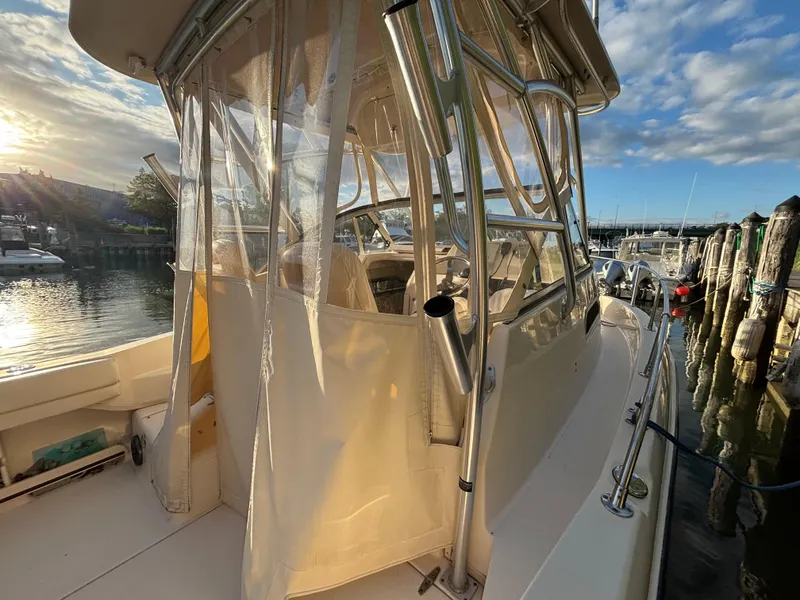 Slide: The Image of 2021 Grady-White Gulfstream 232 boat docked at sunset, featuring clear enclosure and stainless steel frame. - 28