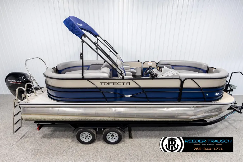 Slide: The Image of 2021 Trifecta 22 CS pontoon boat on trailer, featuring blue and gray design. - 0