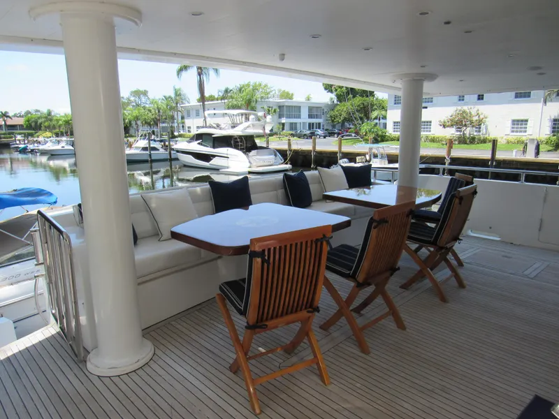 Slide: The Image of Outdoor seating area on a 2002 Hargrave Raised Pilothouse yacht, featuring wooden chairs and tables. - 14