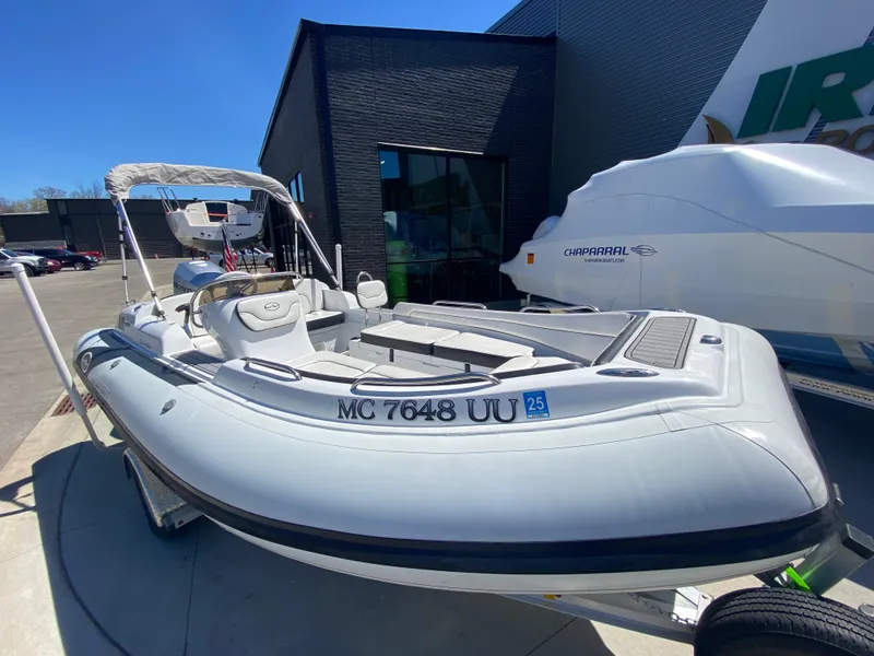 Slide: The Image of 2021 Walker Bay Generation 525 DLX boat displayed outdoors on a sunny day. - 2