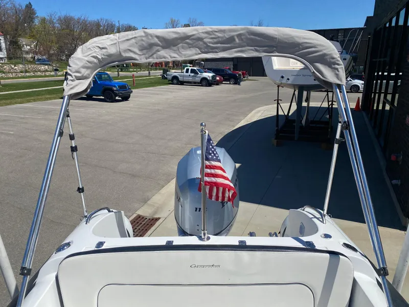 Slide: The Image of 2021 Walker Bay Generation 525 DLX boat with American flag and bimini top in a parking area. - 20