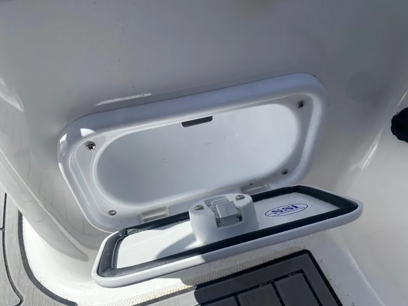 Slide: The Image of Walker Bay Generation 525 DLX 2021 boat storage compartment, open lid, white interior. - 48