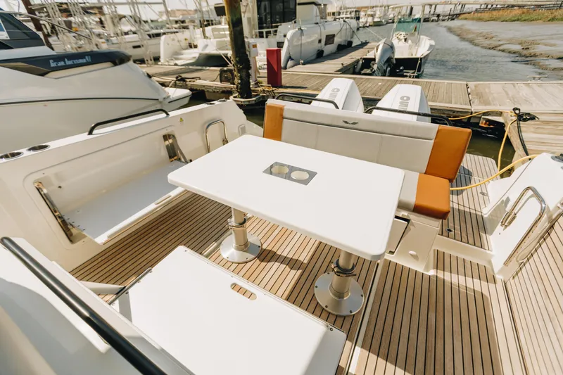 Slide: The Image of 2023 Beneteau Flyer 9 SPACEdeck boat interior with seating and table, docked at marina. - 5