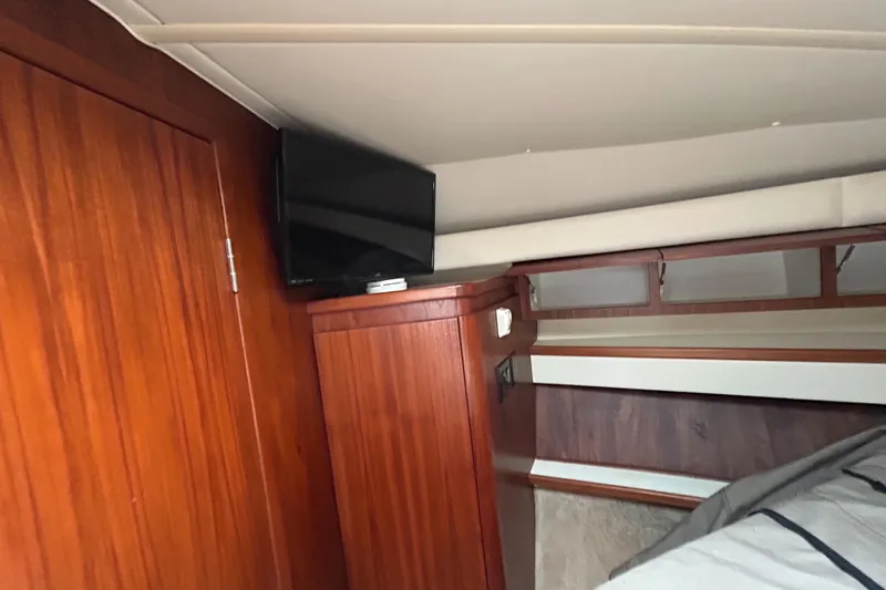 Slide: The Image of 1999 Tiara Yachts 400 Express cabin interior with wood paneling and mounted TV. - 15