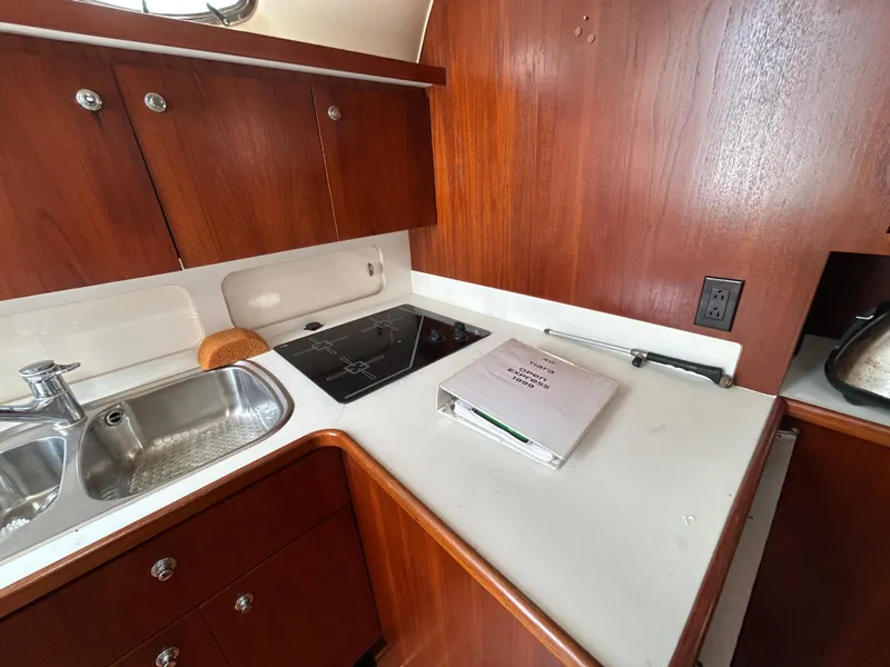 Slide: The Image of 1999 Tiara Yachts 400 Express kitchen with wood cabinets, sink, and stovetop. - 19