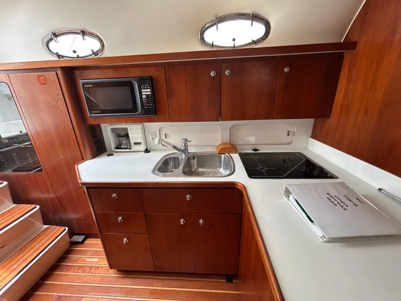 Slide: The Image of 1999 Tiara Yachts 400 Express kitchen with wood cabinetry, sink, microwave, and stovetop. - 20