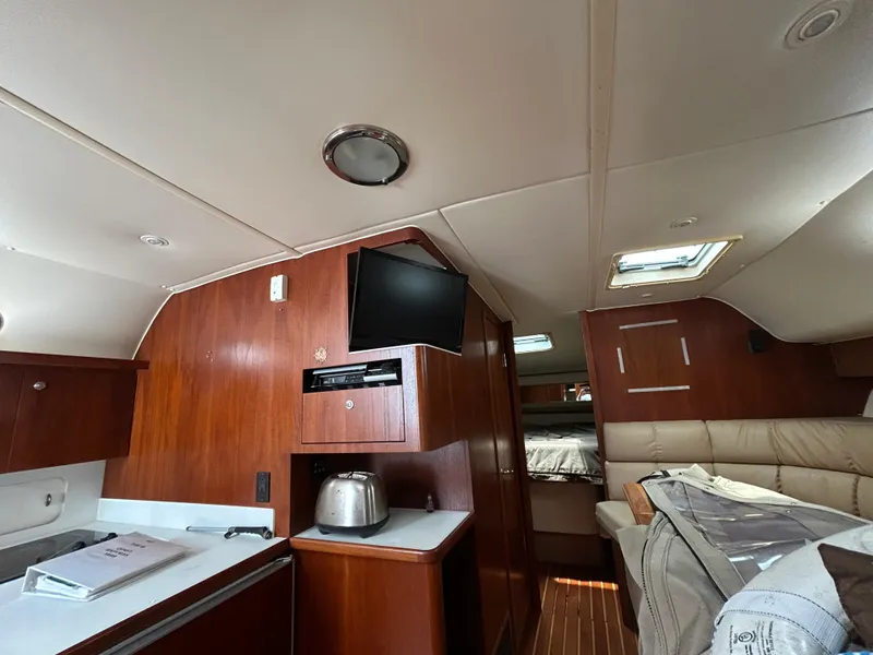 Slide: The Image of 1999 Tiara Yachts 400 Express interior with wood finish, kitchenette, and seating area. - 25