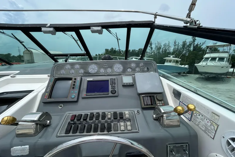 Slide: The Image of 1999 Tiara Yachts 400 Express helm with navigation controls and gauges, docked near other boats. - 30