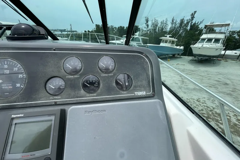 Slide: The Image of 1999 Tiara Yachts 400 Express dashboard with gauges, docked boats in background. - 34