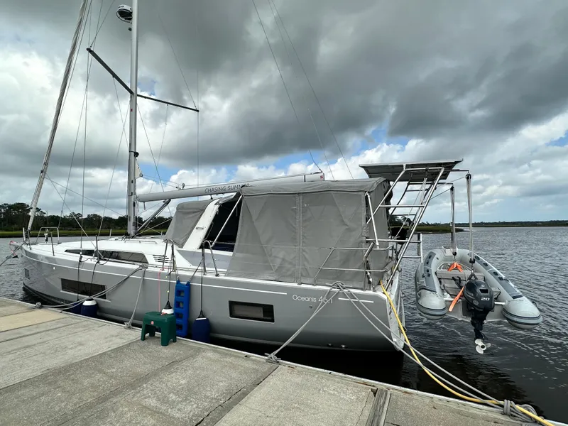 The Image of 2023 Beneteau Oceanis 46.1 sailboat docked with dinghy, under cloudy sky. - 0