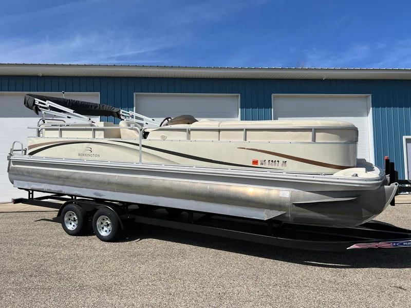 Slide: The Image of 2004 Bennington 2575 RLX pontoon boat on trailer, parked outside blue building. - 0