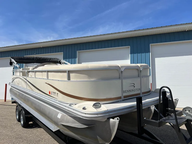 Slide: The Image of 2004 Bennington 2575 RLX pontoon boat on trailer, parked near blue building. - 17