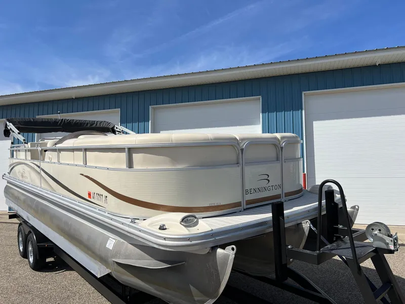 Slide: The Image of 2004 Bennington 2575 RLX pontoon boat on trailer, parked near blue building. - 18