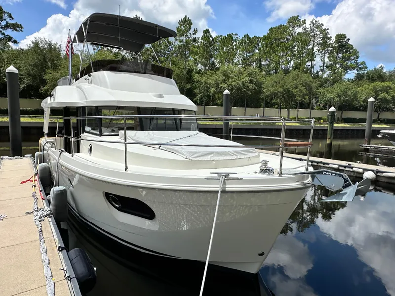 Slide: The Image of 2022 Beneteau Swift Trawler 35 docked at marina, surrounded by trees and calm water. - 4