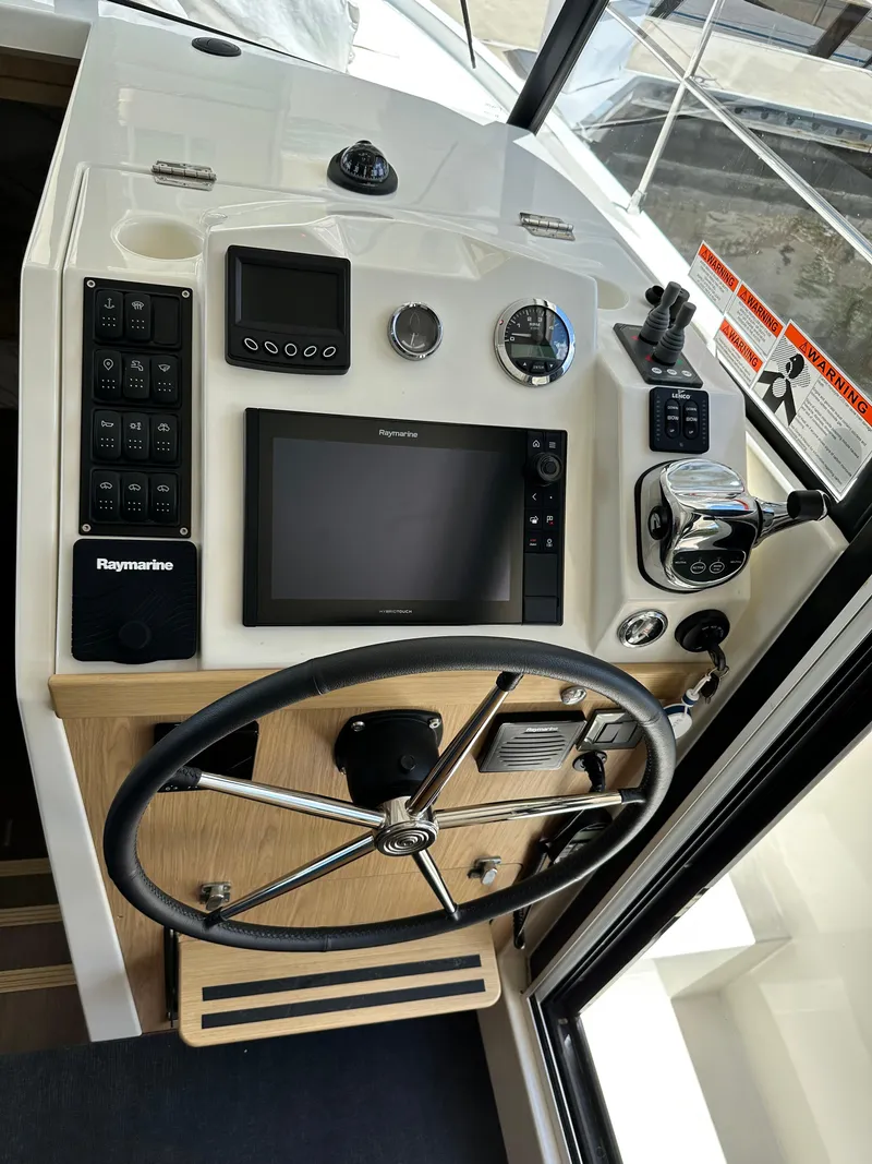 Slide: The Image of 2022 Beneteau Swift Trawler 35 helm with Raymarine navigation system and steering wheel. - 46
