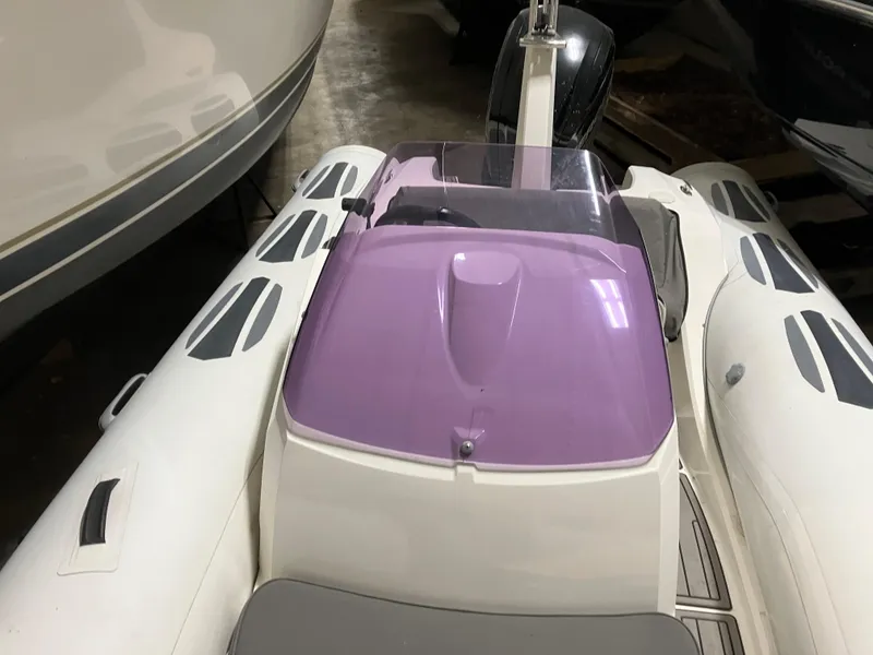 Slide: The Image of 2015 Brig Eagle 480 boat with purple windshield, docked indoors. - 5