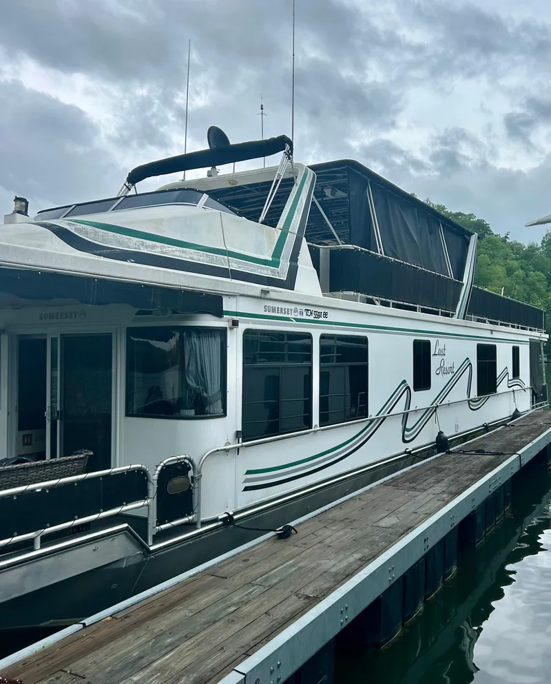 Slide: The Image of 2002 Sumerset houseboat docked, featuring sleek design and spacious upper deck. - 1