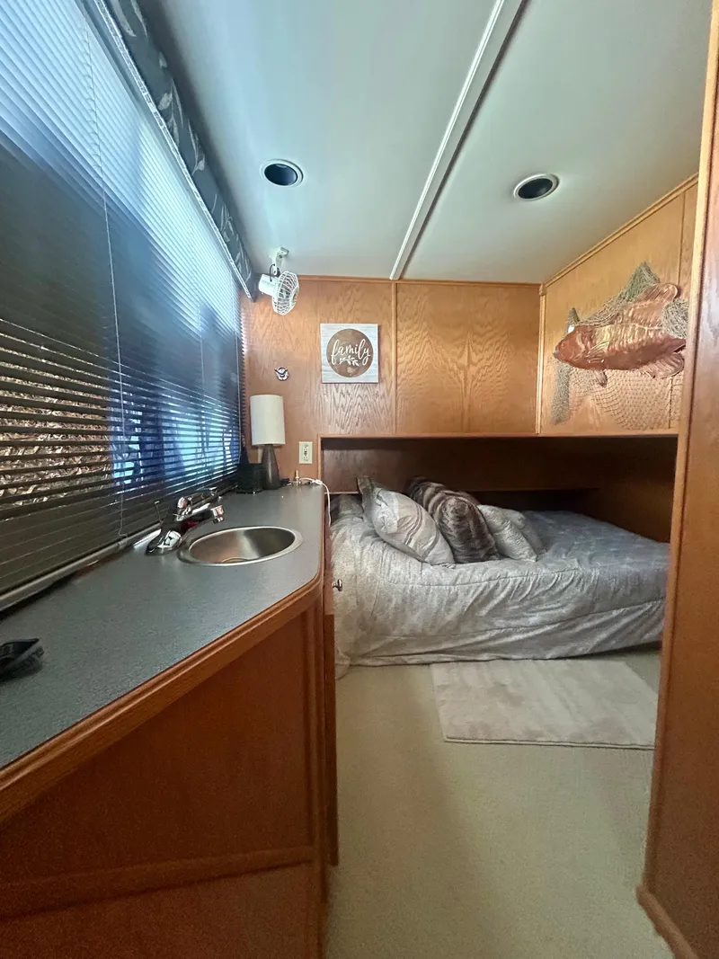 Slide: The Image of Interior of a 2002 Sumerset houseboat bedroom with bed, sink, and fish wall art. - 11