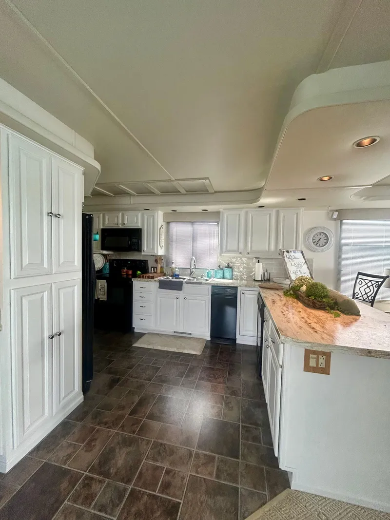 Slide: The Image of Modern kitchen interior of 2002 Sumerset houseboat with white cabinets and dark flooring. - 13