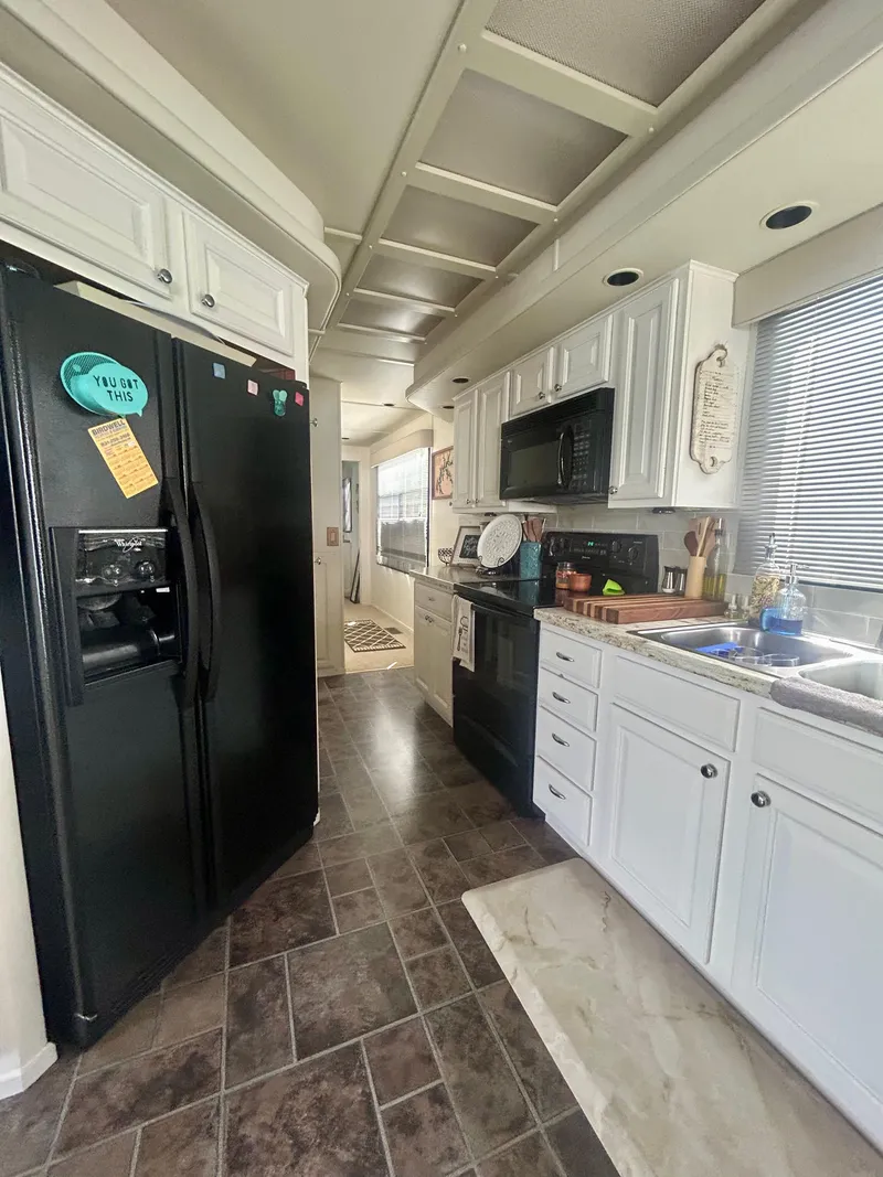 Slide: The Image of Modern kitchen interior in a 2002 Sumerset houseboat with black appliances and white cabinetry. - 14