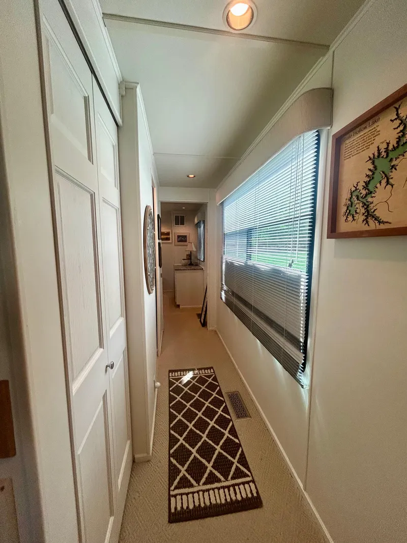 Slide: The Image of Narrow hallway inside a 2002 Sumerset houseboat, featuring carpet and wall art. - 15